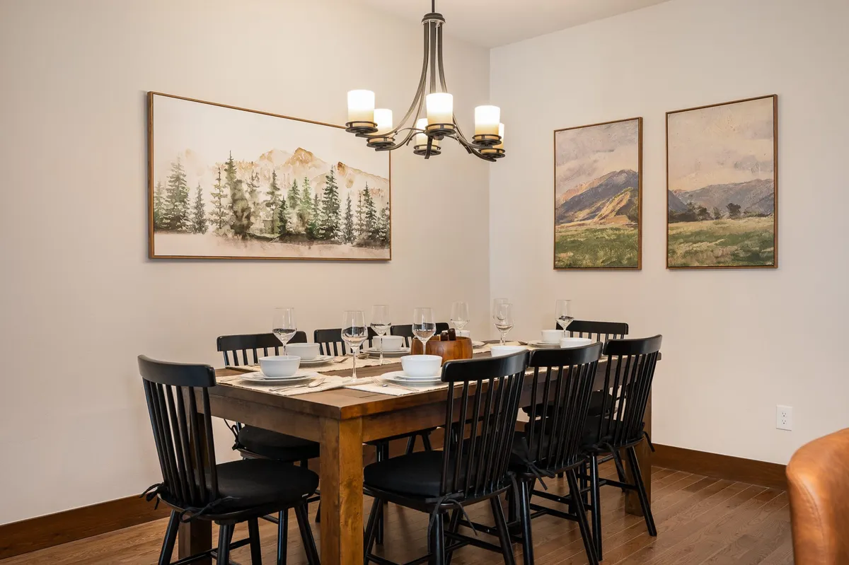 A spacious dining area with a central table beneath a chandelier, art-adorned walls, and an inviting layout. The scene is set for group meals, conversation, and special celebrations, emphasizing connection and comfort.